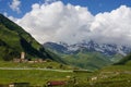 view of green grass meadow with houses and buildings and mountains on ÃâÃÂ background, Ushguli,